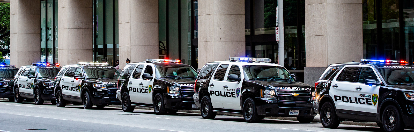 Image of six houston Police cars in a line in front of Houston Police Department building